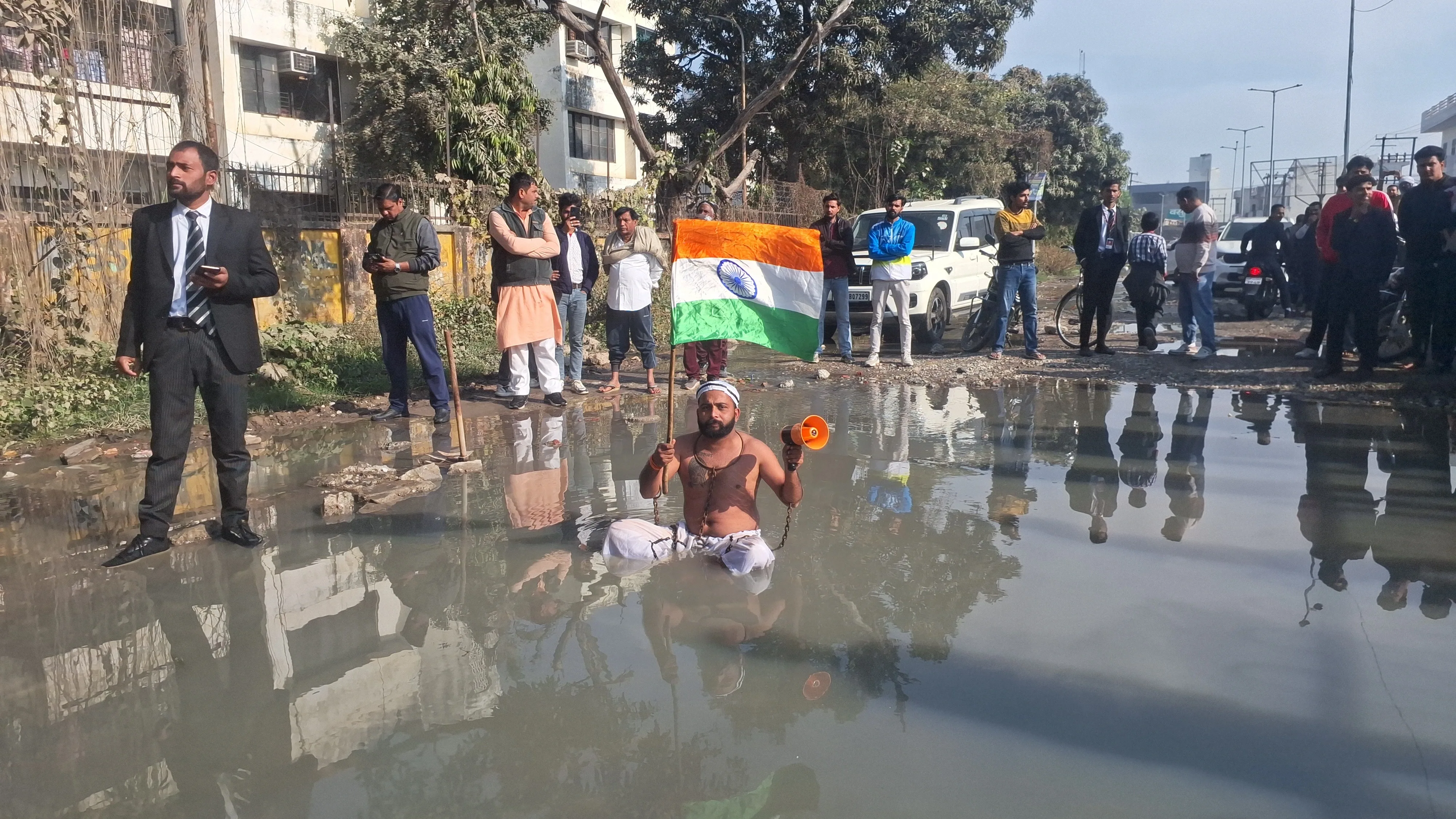 मुज़फ्फरनगर में टूटी सड़क के लिए घंटों गंदे पानी में बैठा युवक, मचा हंगामा तो जागे मंत्री और चेयरमैन, दिया आश्वासन